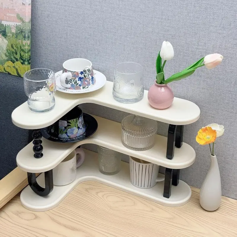 White curved three-tier shelf holding cups and coffee jars